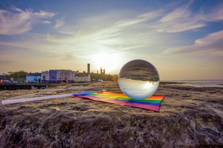 An LGBT flag and ball in front on the pier