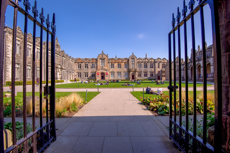 St Salvator's Quadrangle through open gates where students are sitting on the grass.