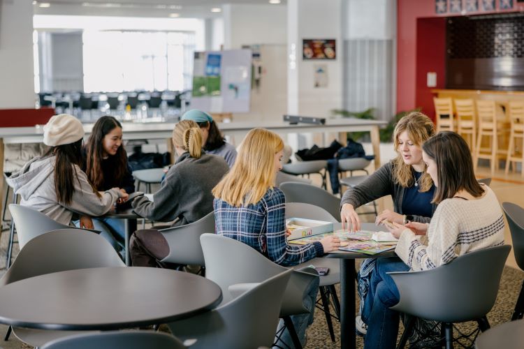Group of students sitting around a table playing a board game at David Russell Apartments