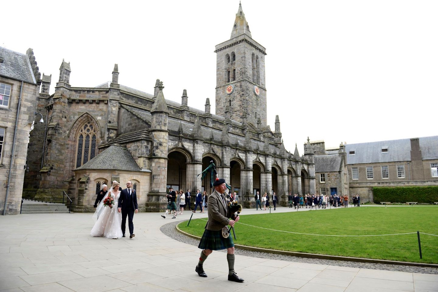 Piper leading bride and groom around the quadrangle