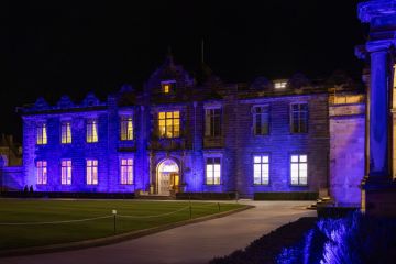 Historic University buildings and quadrangle lit up at night with blue uplighters