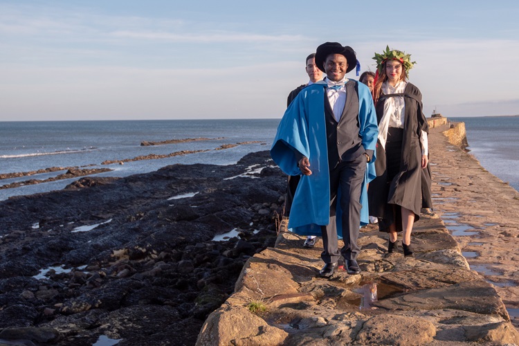 students in graduation robes on rocks