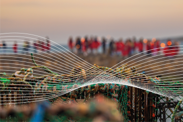 Students walking on the cross pier with fishing nets and lobster pots in the foreground
