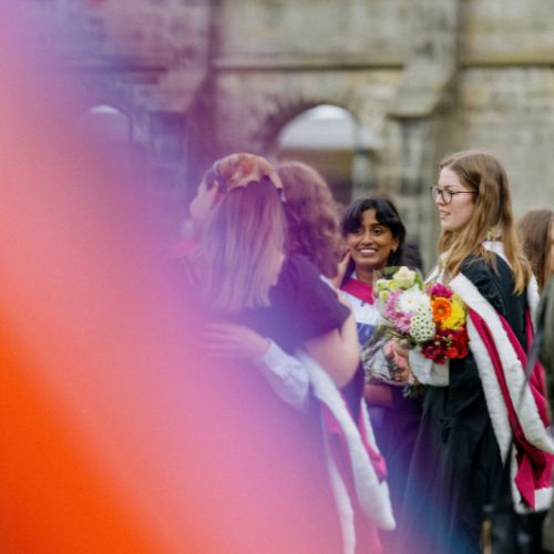 Female students are gathered, smiling and celebrating, in graduation robes.