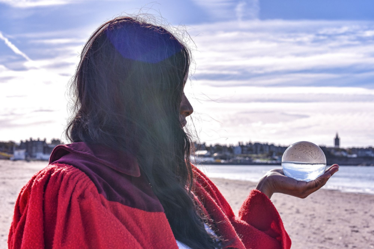 Student on beach holding a glass globe in her hand