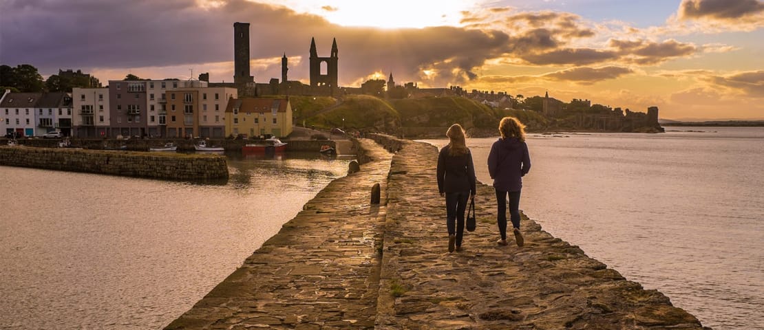 People walking along St Andrews pier at sunset