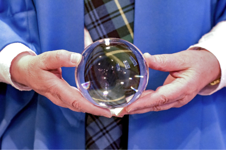 Image of student in blue robes holding glass ball