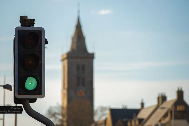 Green traffic light with St Salvator's Chapel tower in the background.