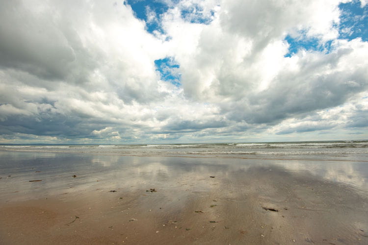 Cloudy sky reflected on wet sand at a beach near the University of St Andrews.