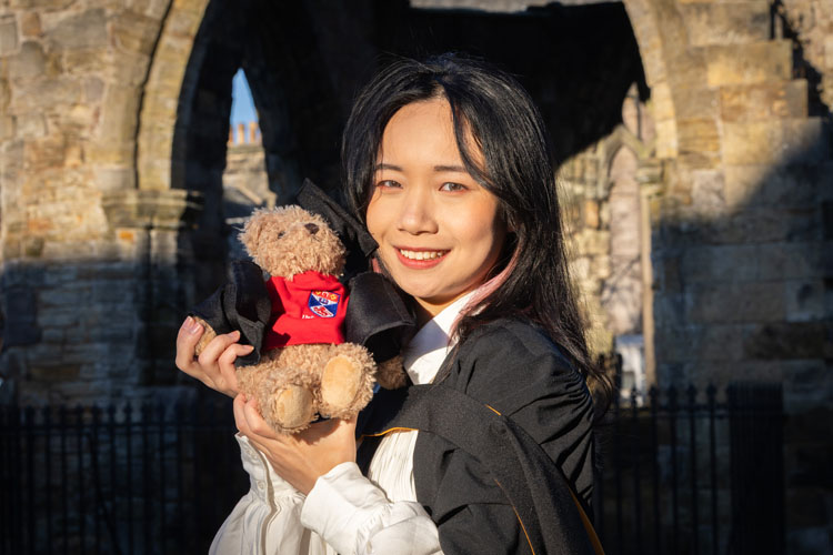 A happy female graduate holding the graduate teddy bear