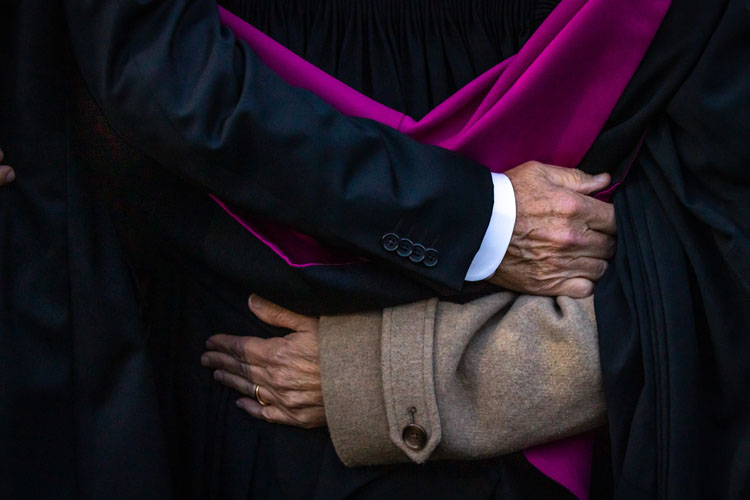 Close up of two arms wrapped around a graduate's back