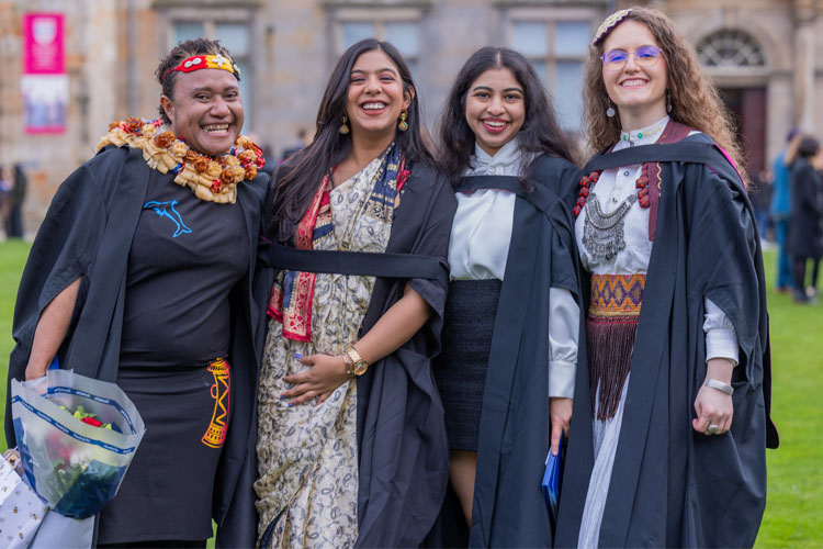 Four graduates in traditional dress standing in St Salvator's Quad