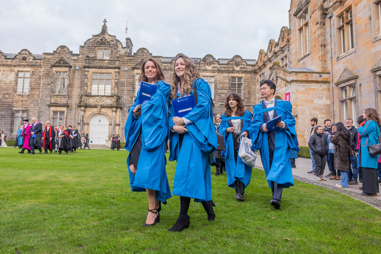 Postgraduate graduates walking on the lawn in St Salvator's Quad
