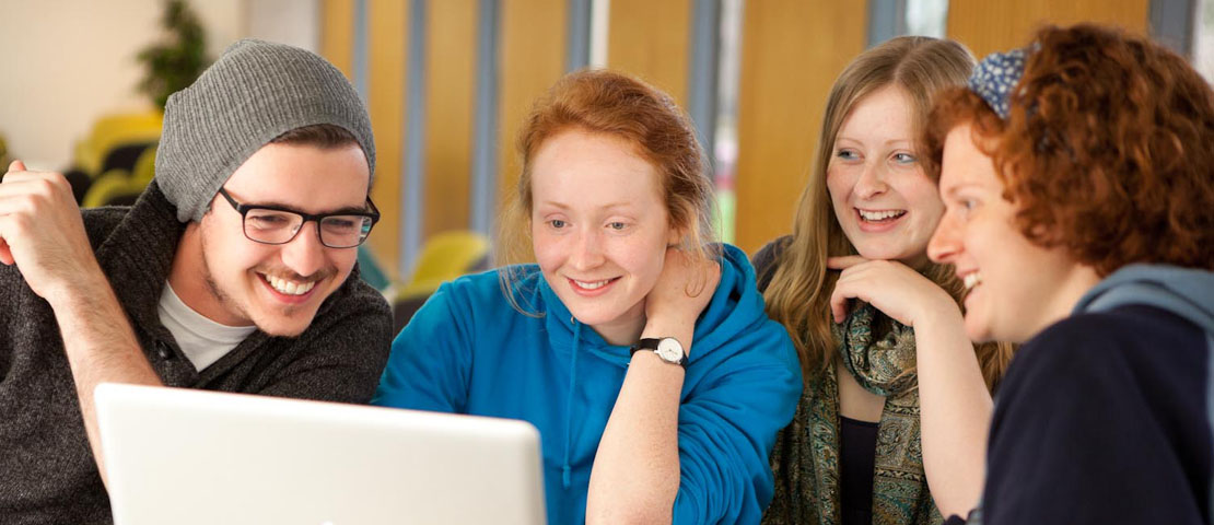 Students gathering around a laptop to study