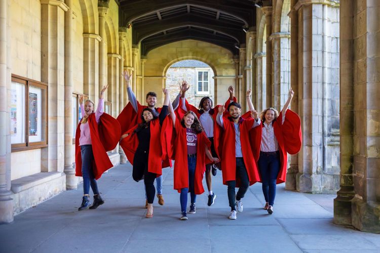 Students in red gowns leaping in the air