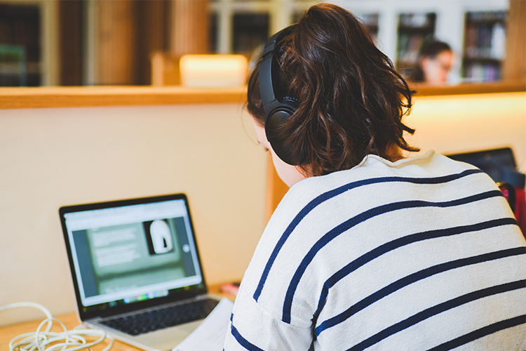 Student in striped top working on laptop