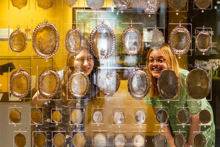Two visitors looking at silver archery medal display