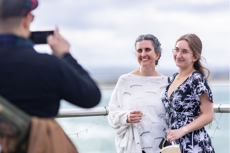 Two people posing for a photograph on a terrace with sea view.