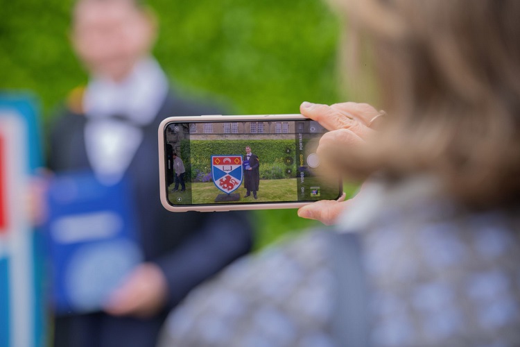 Woman takes photo of student on a mobile phone