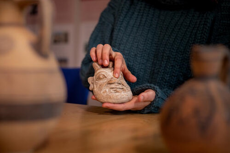 Hands holding an archaeological mask