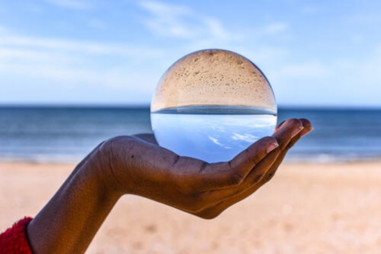 Hand holding a crystal ball on beach