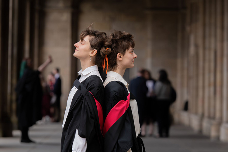 Two graduation students standing back to back in St Salvators