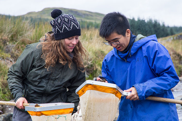 Two students examining nets in a coastal region