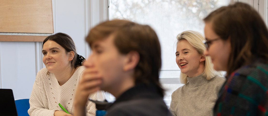 4 students sitting round a table looking towards one side of the room