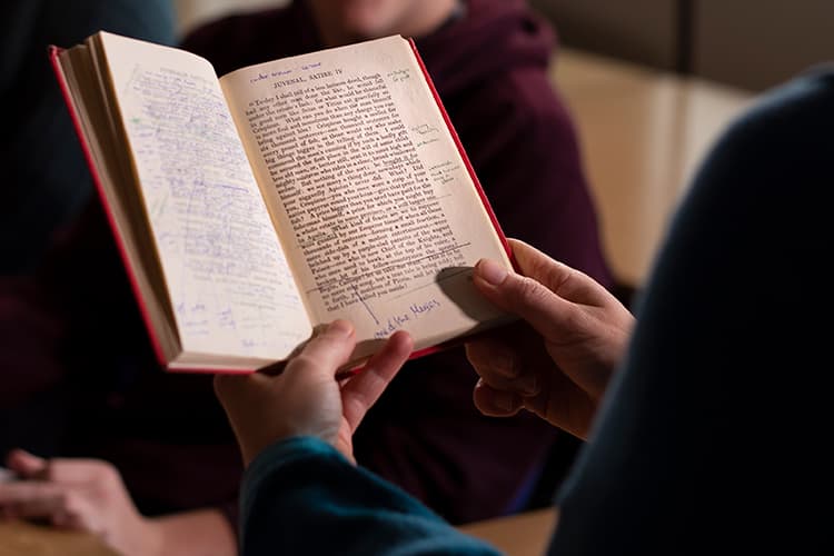 Hands holding a book of Latin texts