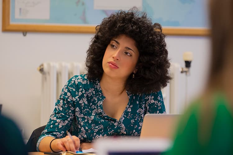 Woman at a table listening and taking notes