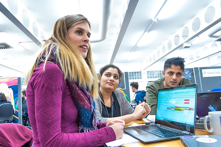 Three postgradaute students sitting around a table in the lab