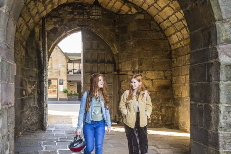 Photo of two students walking through an arch doorway.
