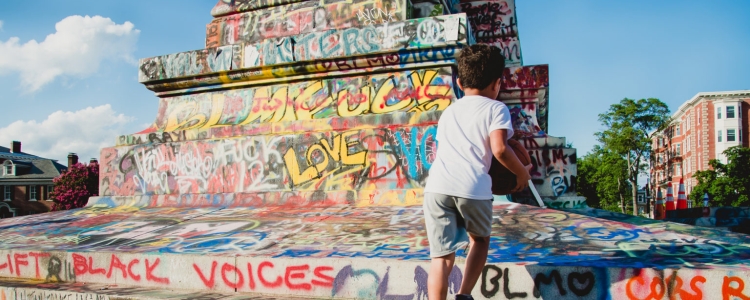 Statue covered in graffiti with boy climbing steps