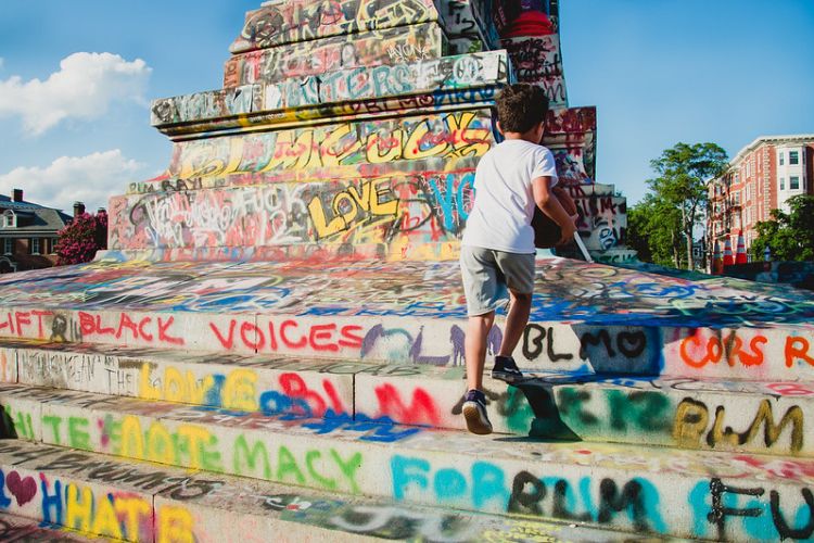 Statue covered in graffiti with boy climbing steps