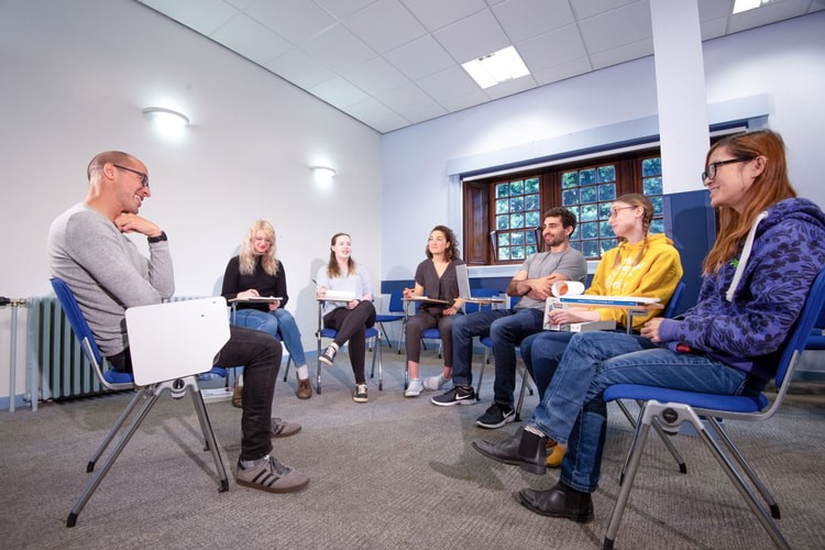 Photo of lecturers and students sitting on chairs in a circle