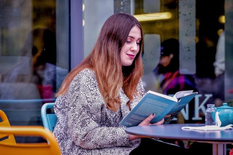 St Andrews student reading outside Rectors cafe, University of St Andrews