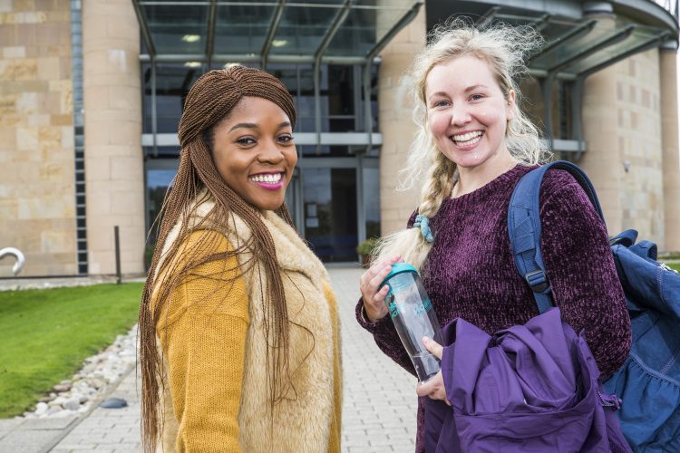 Two smiling students standing in front of Gateway building