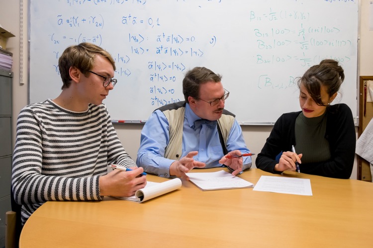 Two students in a discussion with a staff member.