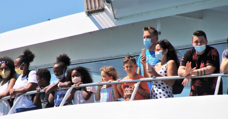 People on a ferry touching the rails.