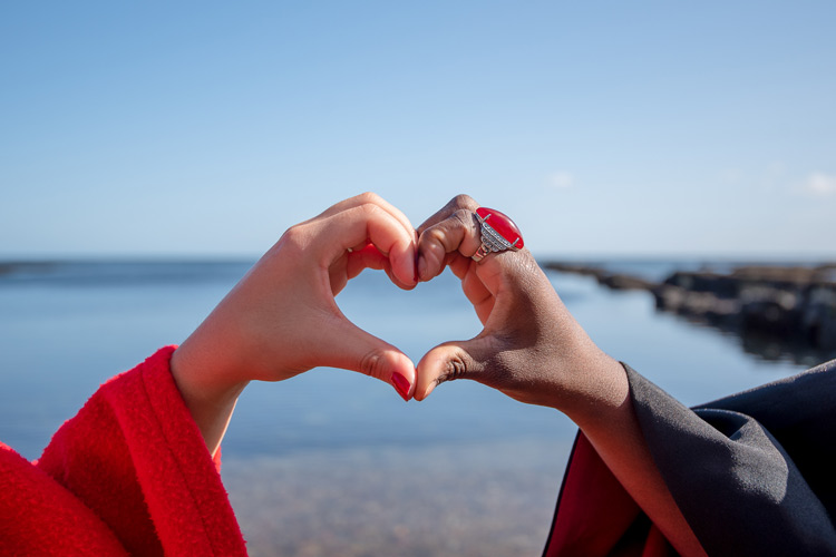 Two hands of different race making a heart shape.