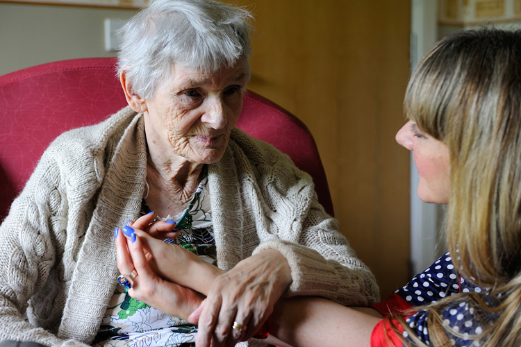 Lady and carer holding hands and smiling