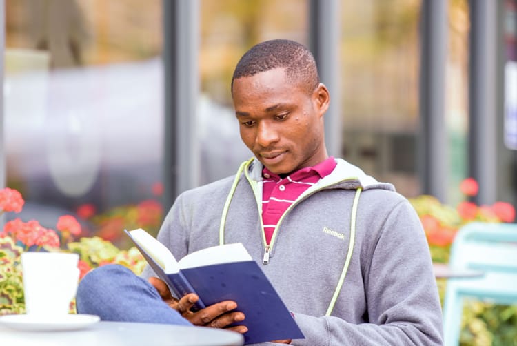 A student reading a book outside the Rector's Cafe in St Andrews.