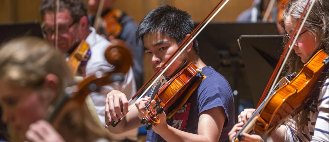 Student playing the violin in a concert band