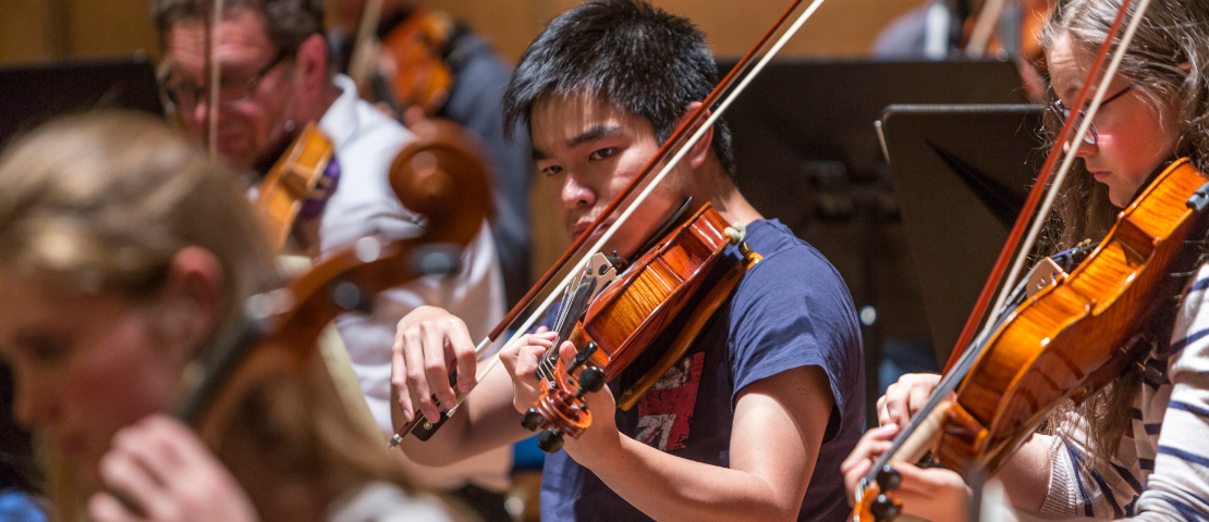 Group of students playing violins on stage