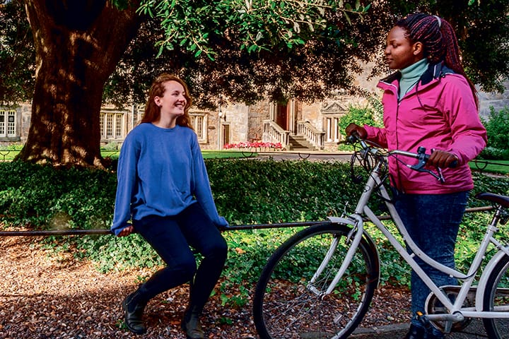 Two students sitting beneath a tree